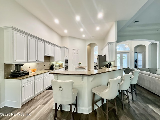 243 Stonewell Dr, Saint Johns, FL 32259 - kitchen featuring arched walkways, a breakfast bar, wood finished floors, recessed lighting, and freestanding refrigerator