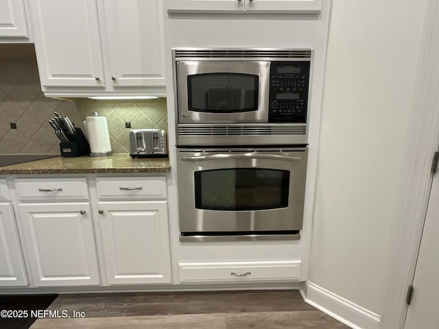 243 Stonewell Dr, Saint Johns, FL 32259 - kitchen with stainless steel appliances, white cabinets, backsplash, dark wood-type flooring, and dark stone countertops
