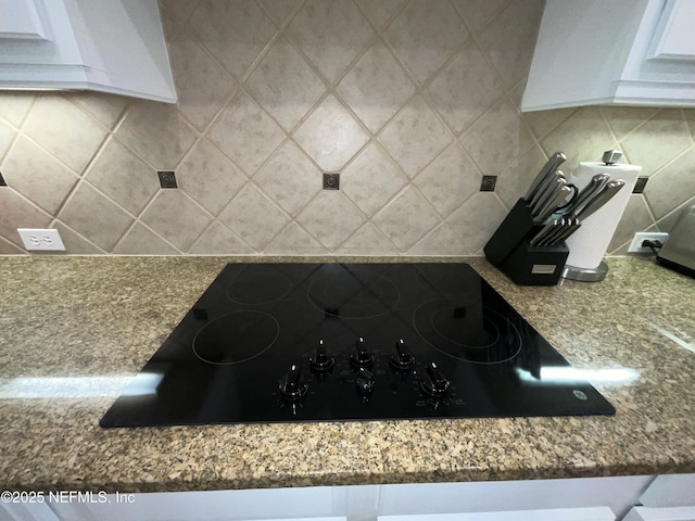243 Stonewell Dr, Saint Johns, FL 32259 - kitchen view of black electric stovetop, backsplash, white cabinetry, and stone counters