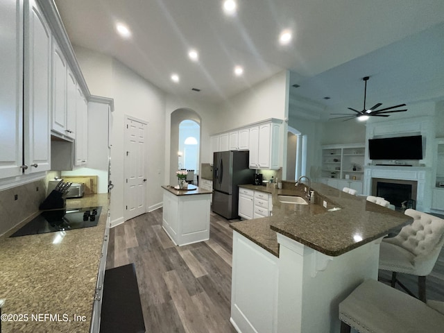 243 Stonewell Dr, Saint Johns, FL 32259 - kitchen with arched walkways, black electric cooktop, a ceiling fan, stainless steel refrigerator with ice dispenser, and a kitchen island