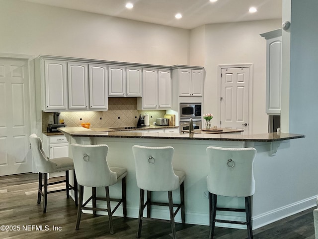 243 Stonewell Dr, Saint Johns, FL 32259 - kitchen featuring stainless steel appliances, a breakfast bar area, decorative backsplash, dark wood-type flooring, and recessed lighting