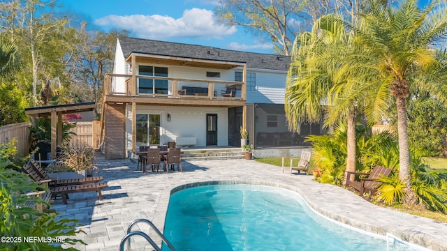 rear view of house featuring a balcony, fence, an outdoor pool, and a patio