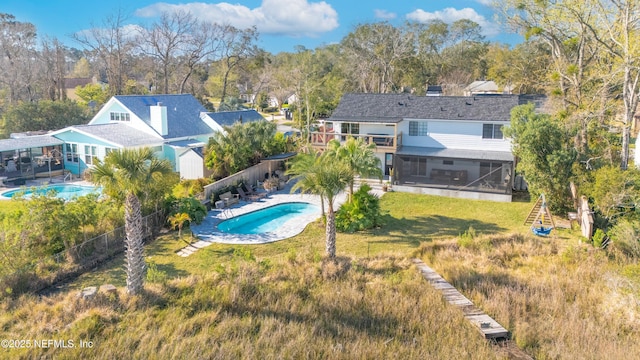 back of house with a yard, a sunroom, a fenced backyard, and an outdoor pool