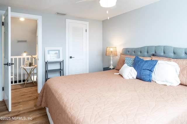 bedroom with ceiling fan, wood finished floors, and visible vents