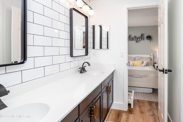 ensuite bathroom featuring double vanity, a sink, backsplash, and ensuite bathroom