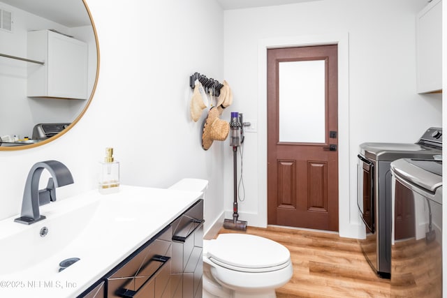 bathroom with toilet, wood finished floors, vanity, visible vents, and independent washer and dryer