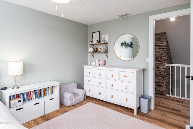 bedroom with a textured ceiling, visible vents, and light wood-style floors