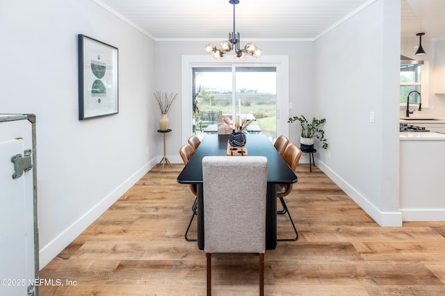 dining space with a chandelier, light wood-type flooring, baseboards, and crown molding