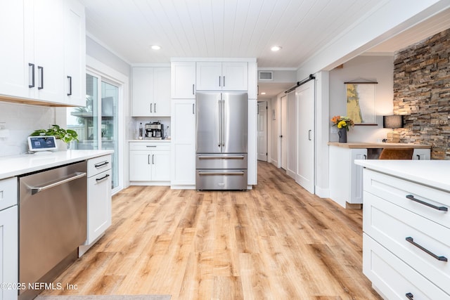 kitchen with a barn door, visible vents, appliances with stainless steel finishes, light countertops, and white cabinetry