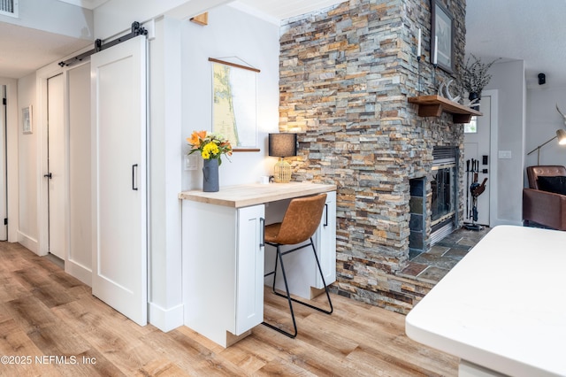 kitchen with a barn door, a breakfast bar area, light wood-type flooring, and wood counters