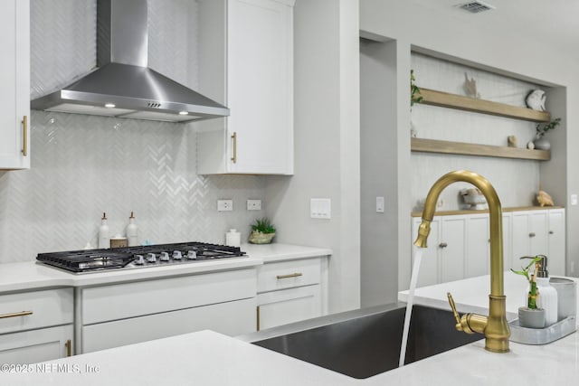 kitchen with open shelves, wall chimney range hood, and white cabinetry