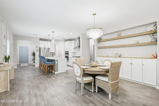 dining space featuring baseboards, recessed lighting, light wood-style flooring, and a notable chandelier