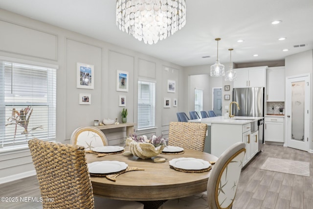 dining space featuring light wood-type flooring, visible vents, a decorative wall, and recessed lighting