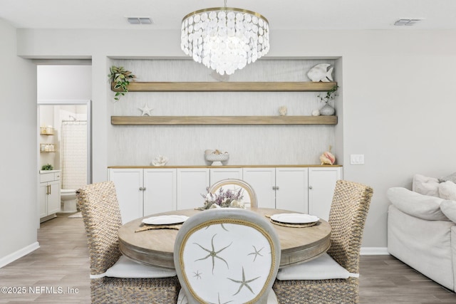 dining space featuring light wood-style floors, visible vents, baseboards, and an inviting chandelier