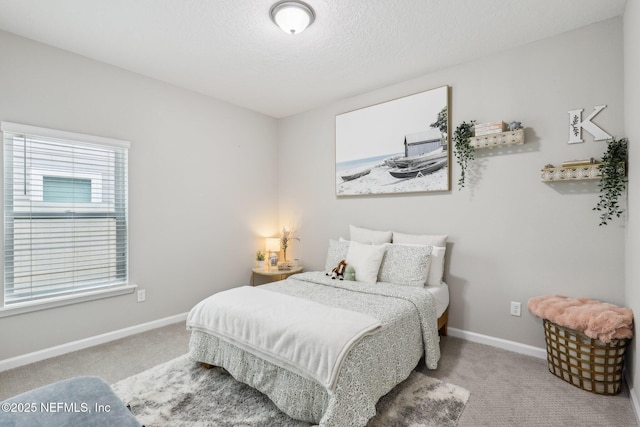 bedroom with light carpet, baseboards, and a textured ceiling