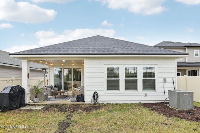 back of property with a shingled roof, fence, cooling unit, and a yard