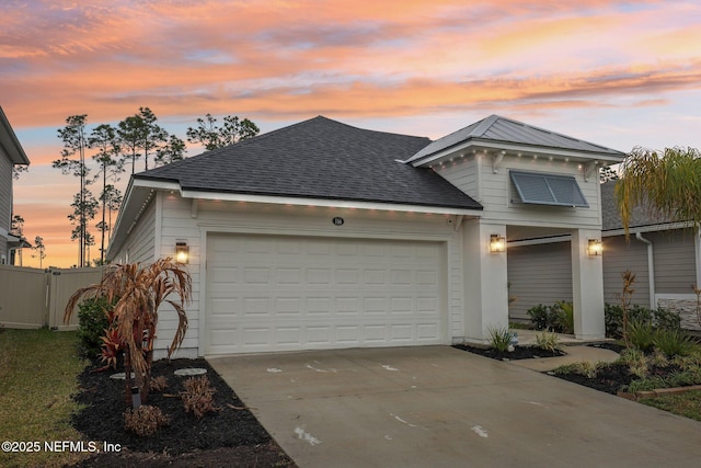 view of front of house featuring driveway, roof with shingles, an attached garage, and fence