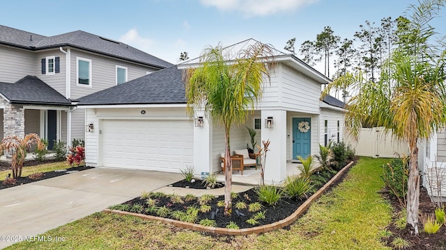 traditional home with a garage, concrete driveway, roof with shingles, and fence