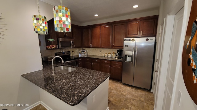 kitchen with appliances with stainless steel finishes, dark stone countertops, a peninsula, a sink, and backsplash