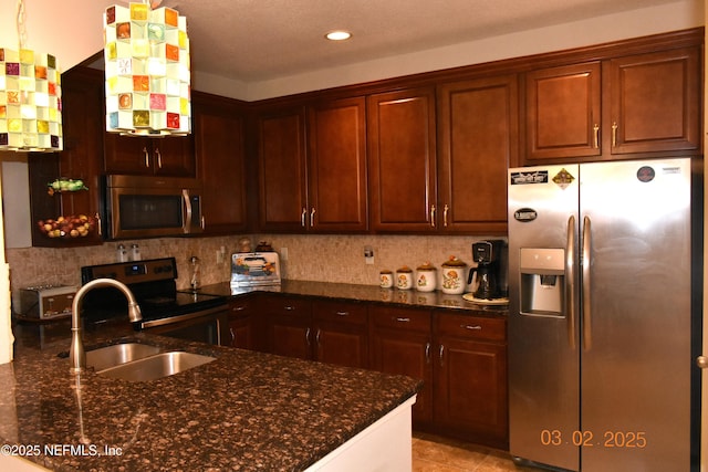 kitchen featuring stainless steel appliances, backsplash, dark stone countertops, and a sink