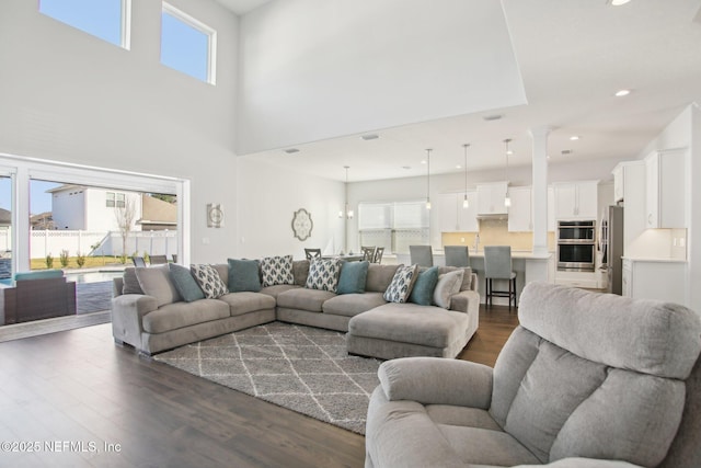 living area with dark wood-style floors, recessed lighting, a wealth of natural light, and ornate columns