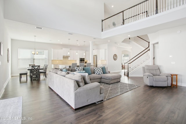 living area featuring dark wood-style floors, baseboards, and stairway