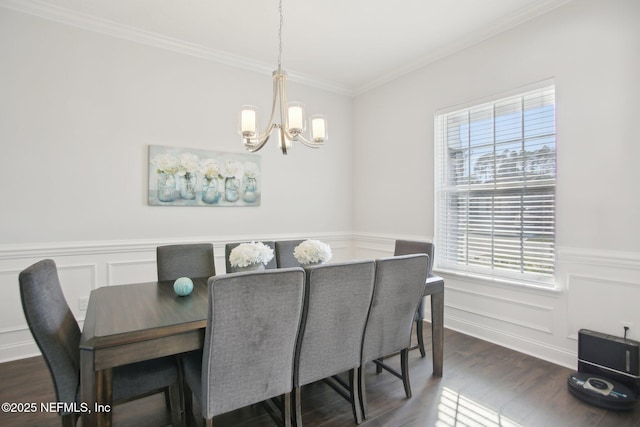 dining room with dark wood-type flooring, a chandelier, a wainscoted wall, and ornamental molding