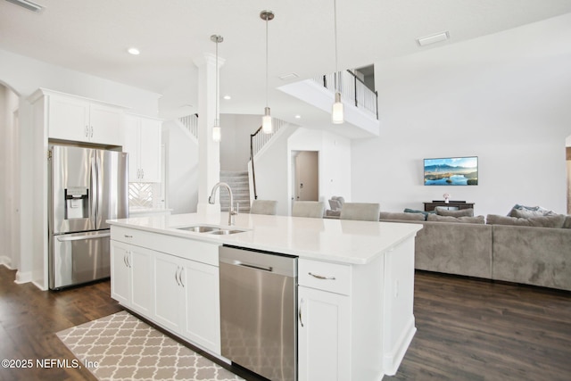 kitchen with stainless steel appliances, dark wood-type flooring, open floor plan, a kitchen island with sink, and a sink