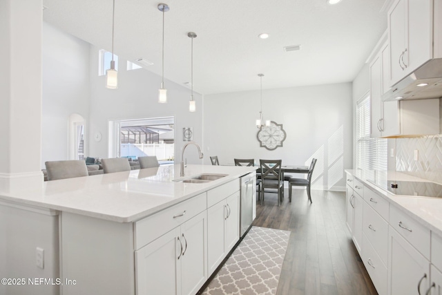 kitchen featuring light countertops, stainless steel dishwasher, dark wood-type flooring, white cabinetry, and a sink