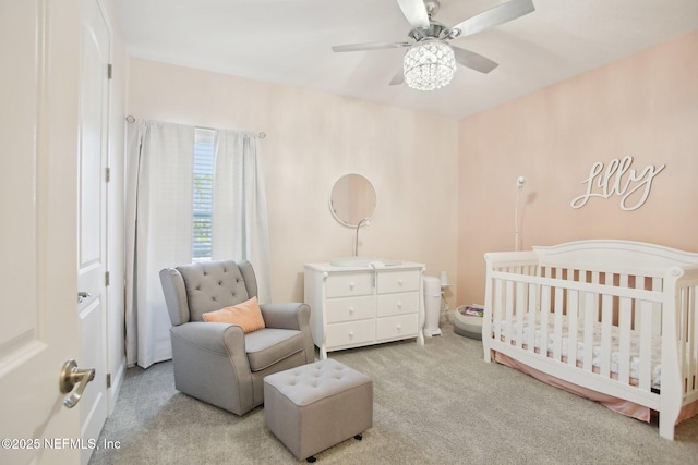 carpeted bedroom featuring a nursery area and ceiling fan