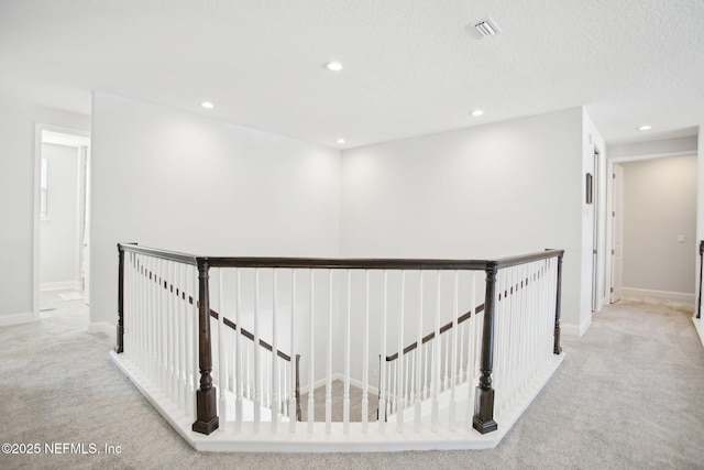 hall with carpet, visible vents, an upstairs landing, and recessed lighting