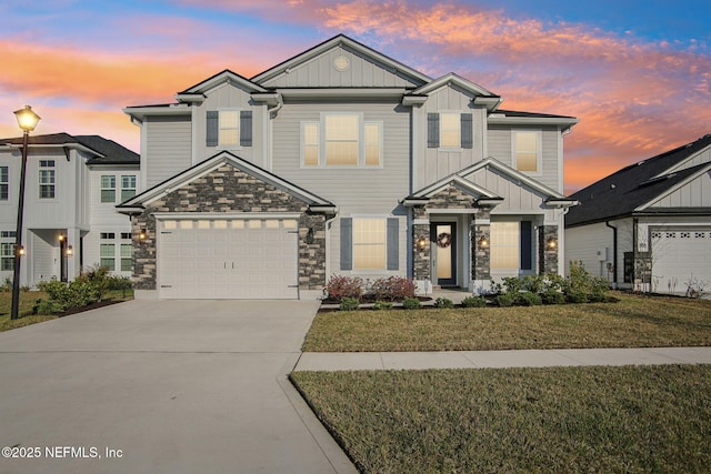 view of front of home featuring a garage, stone siding, concrete driveway, a front lawn, and board and batten siding