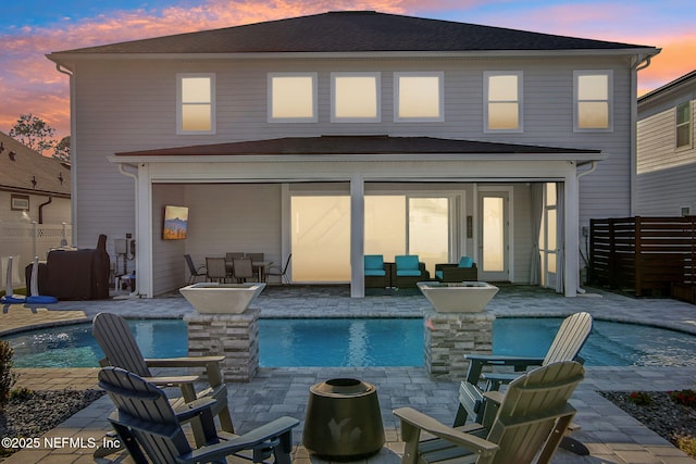 back of house at dusk with fence, an outdoor hangout area, a fenced in pool, and a patio