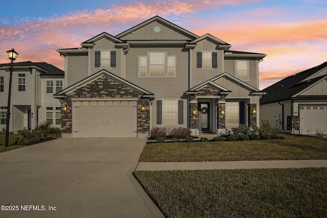 view of front of home featuring driveway, stone siding, a garage, and board and batten siding