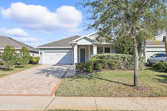 single story home featuring a shingled roof, a front yard, decorative driveway, and an attached garage