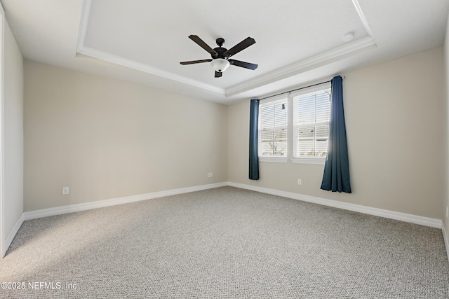 unfurnished room with ceiling fan, carpet floors, a tray ceiling, and baseboards