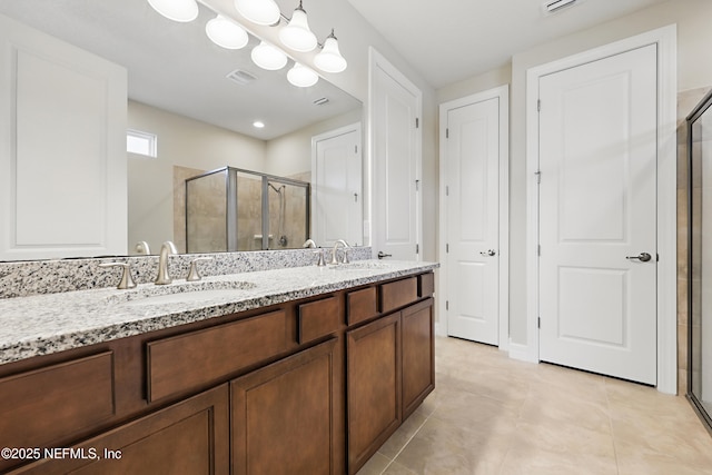 full bathroom with double vanity, tile patterned flooring, a sink, and a shower stall