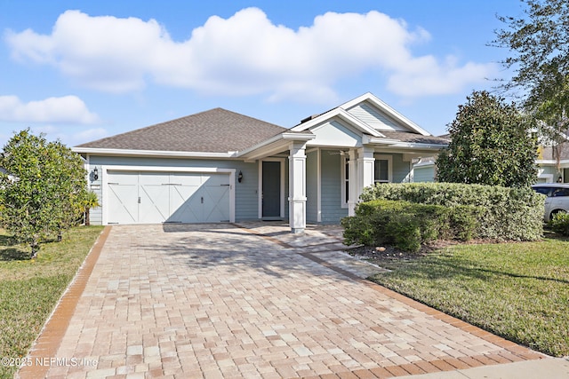 single story home with a front lawn, decorative driveway, an attached garage, and a shingled roof