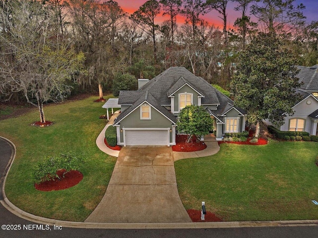 traditional-style house featuring a garage, a yard, and driveway