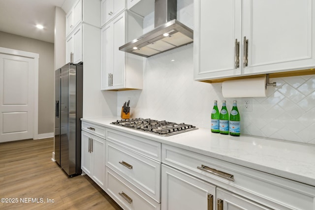 kitchen featuring wall chimney exhaust hood, appliances with stainless steel finishes, light wood-style flooring, and white cabinets