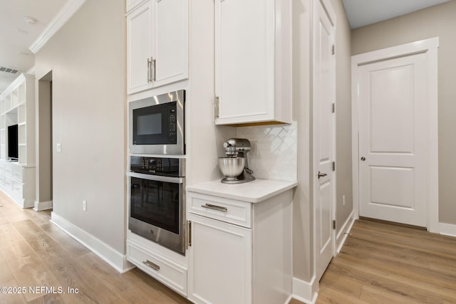 kitchen featuring oven, built in microwave, light countertops, decorative backsplash, and light wood finished floors