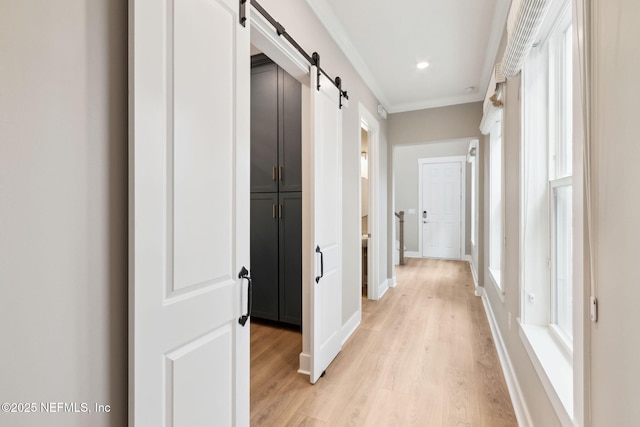 corridor with a barn door, baseboards, light wood-style flooring, crown molding, and recessed lighting