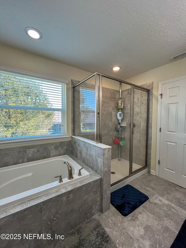 full bathroom featuring a garden tub, a shower stall, visible vents, and a textured ceiling