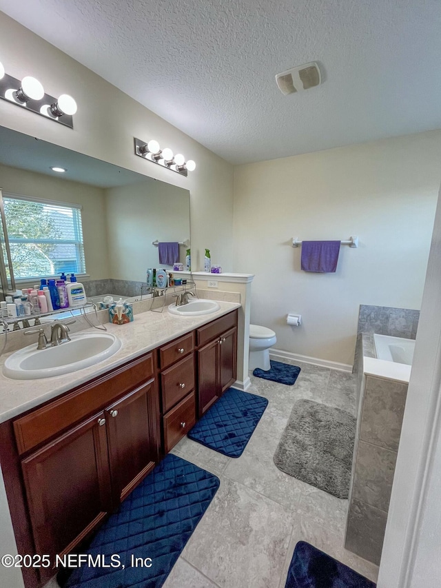 full bath featuring double vanity, toilet, a sink, and a bath