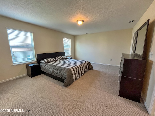 carpeted bedroom featuring visible vents, baseboards, and a textured ceiling