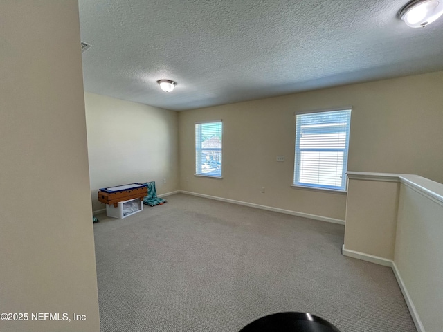 carpeted empty room with a healthy amount of sunlight, visible vents, baseboards, and a textured ceiling