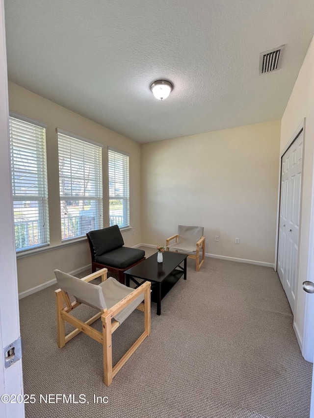 sitting room featuring baseboards, carpet, visible vents, and a textured ceiling