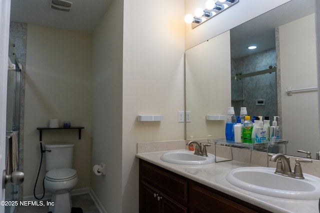 bathroom featuring double vanity, a sink, toilet, and a shower stall