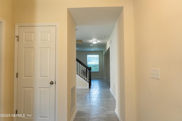 hallway with visible vents, stairway, and baseboards