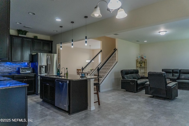 kitchen with appliances with stainless steel finishes, open floor plan, a sink, and a kitchen bar